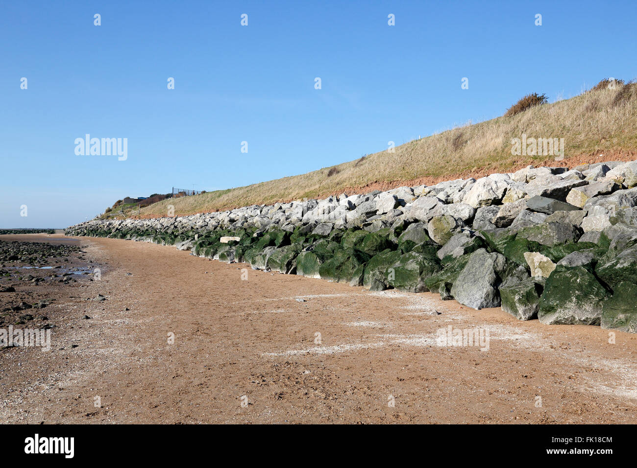 Rock armour rocks and boulders placed at bottom of cliff to prevent erosion by sea on Wirral coast of Dee Estuary UK Stock Photo