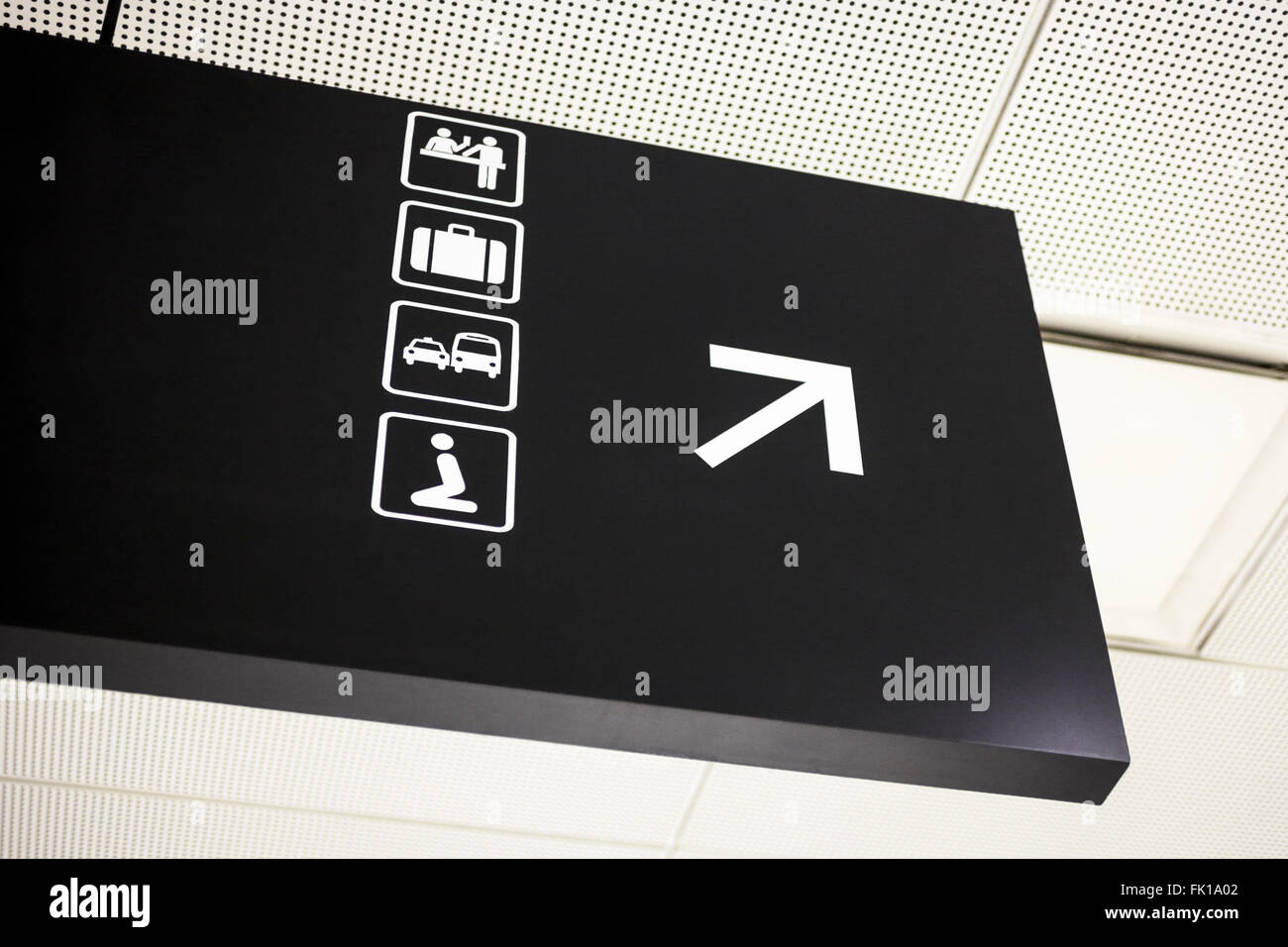 Airport directional arrow sign with symbols for bar, baggage claim, ground transportation, and religious prayer Stock Photo