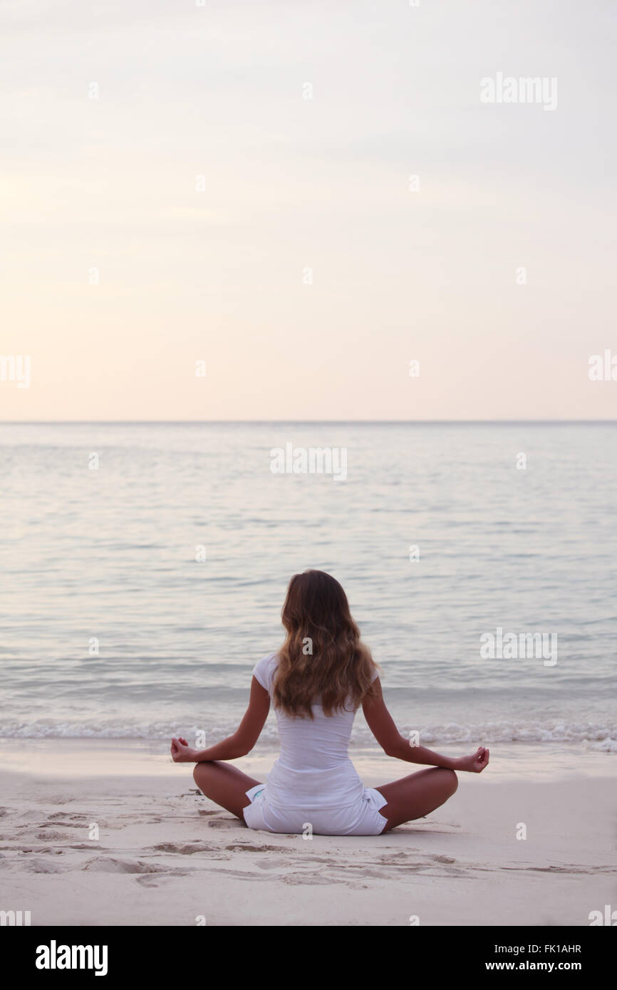 Woman in lotus yoga pose at sunrise on the beach Stock Photo - Alamy