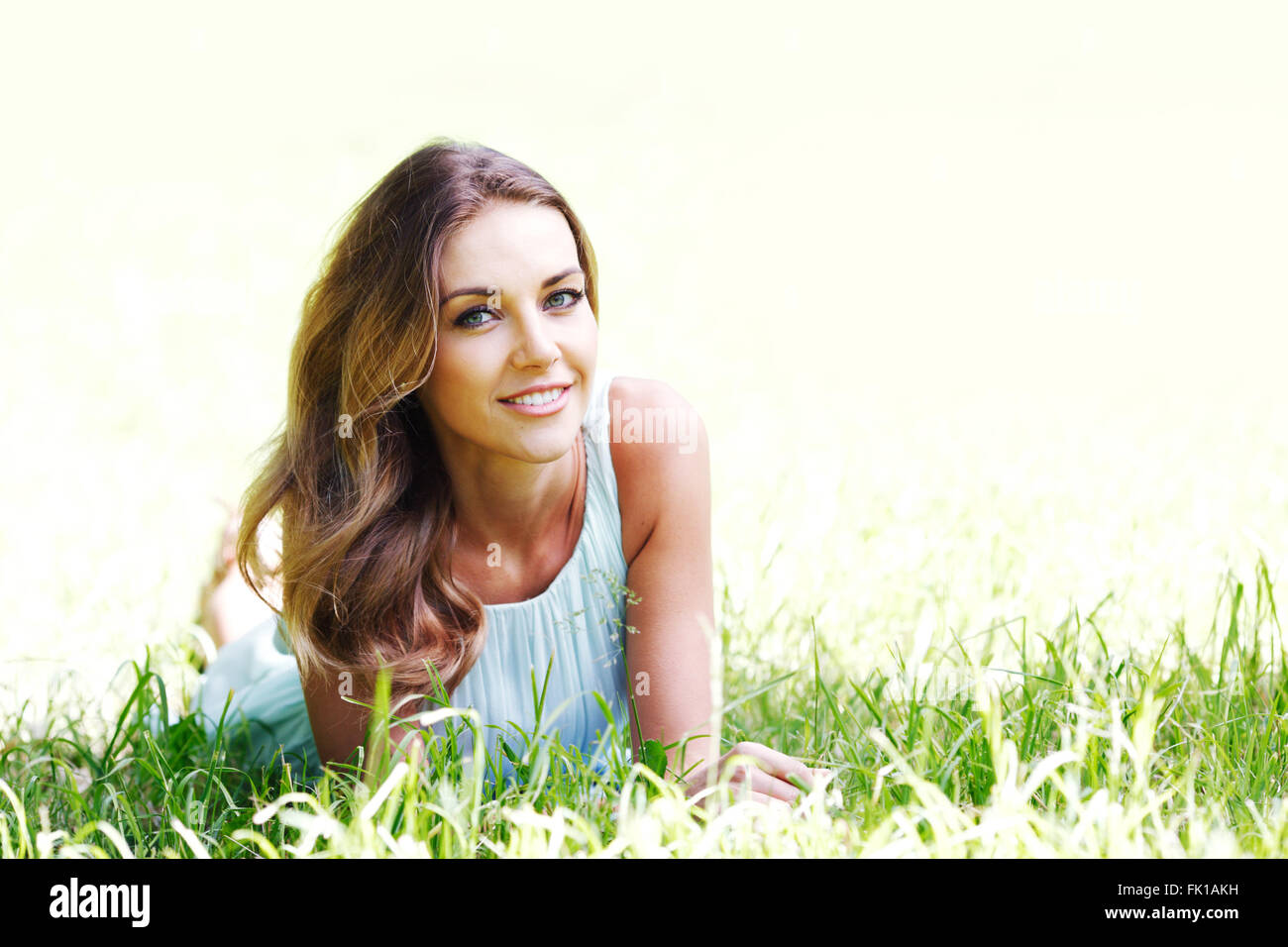 beautiful young woman in blue dress lying on grass Stock Photo - Alamy