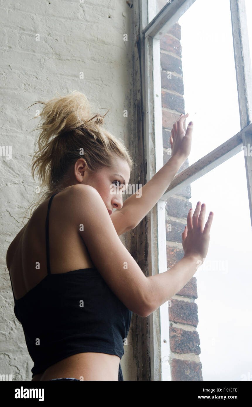 Scared woman looking out of the window Stock Photo