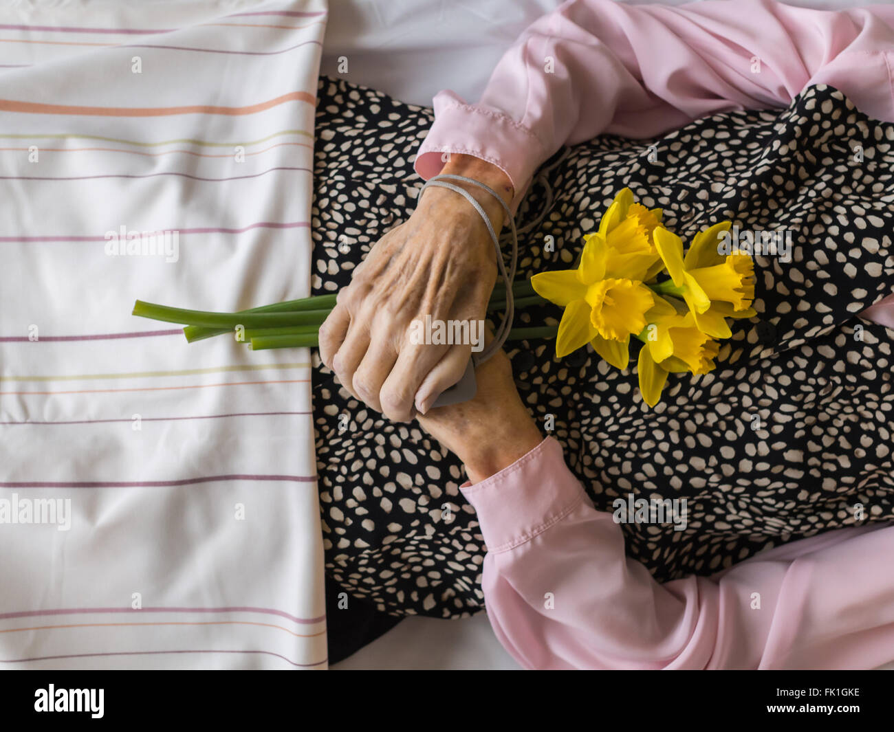 Dead womans crossed hands holding flowers Stock Photo
