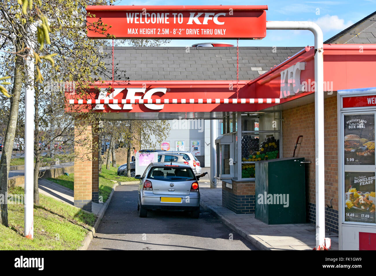 KFC fast food drive through lane with customer in car at ordering window handing back charge card pad obscured number plate  East London England UK Stock Photo