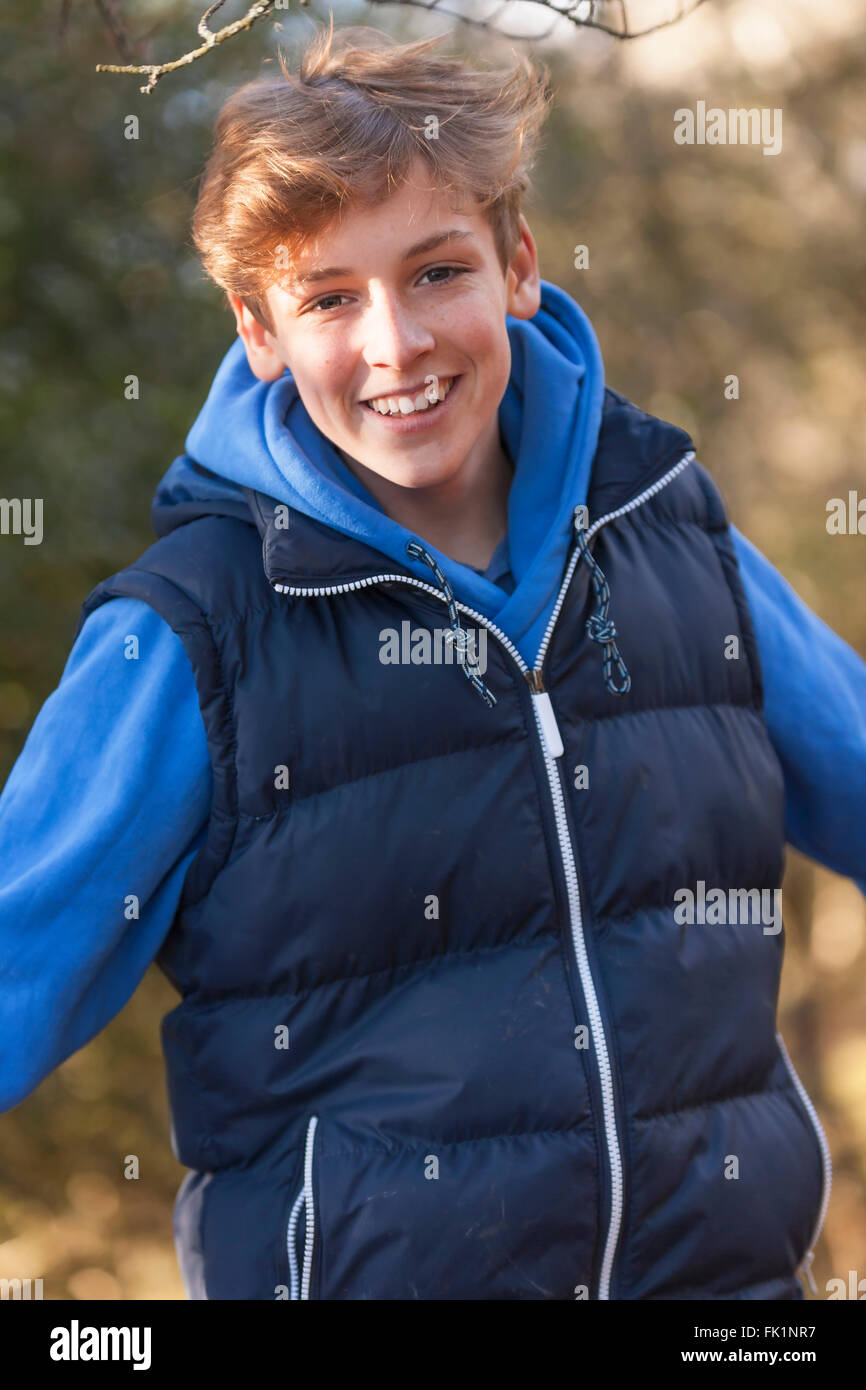Young happy laughing male boy teenager blond child young adult outside in a wood or forest in autumn or fall sunshine Stock Photo