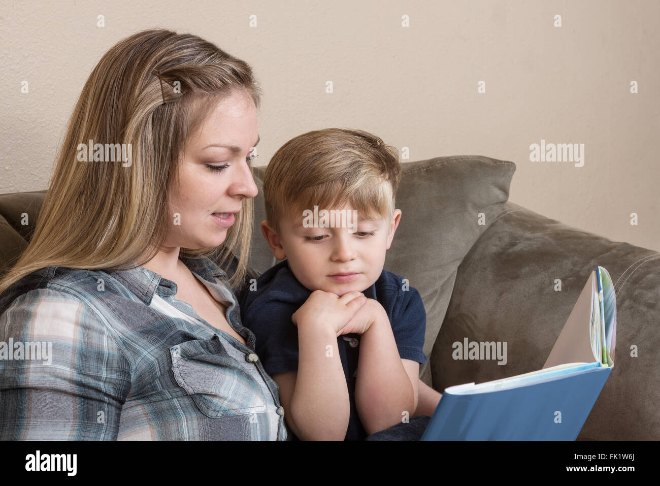 A young boy listens attentively as his mother reads to him. Stock Photo
