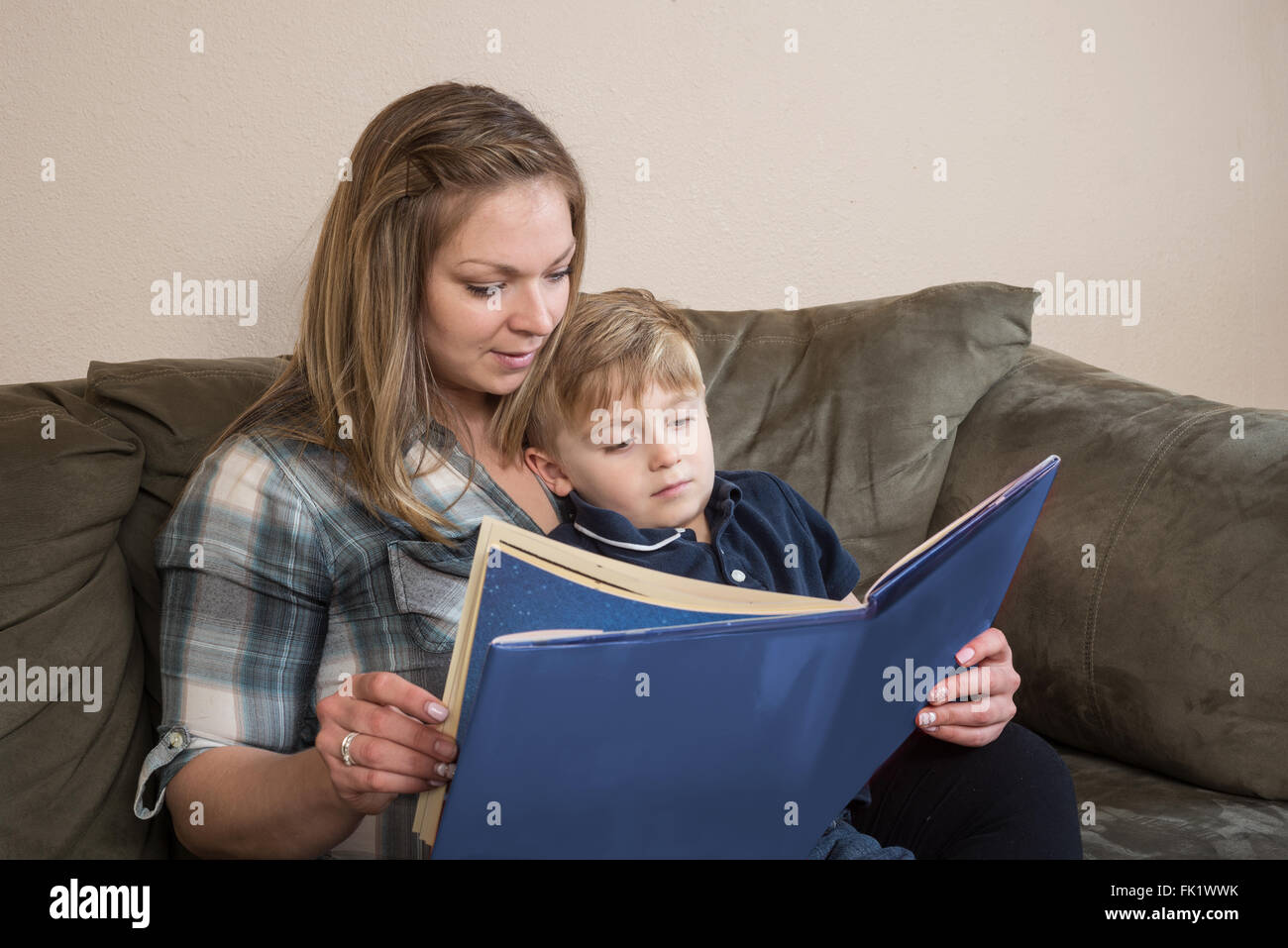 A young boy  quietly listens as his mother reads to him. Stock Photo