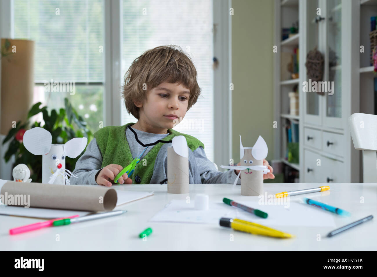 Little boy being creative making homemade paper toys. Supporting creativity, learning by doing, learning through experience. Stock Photo