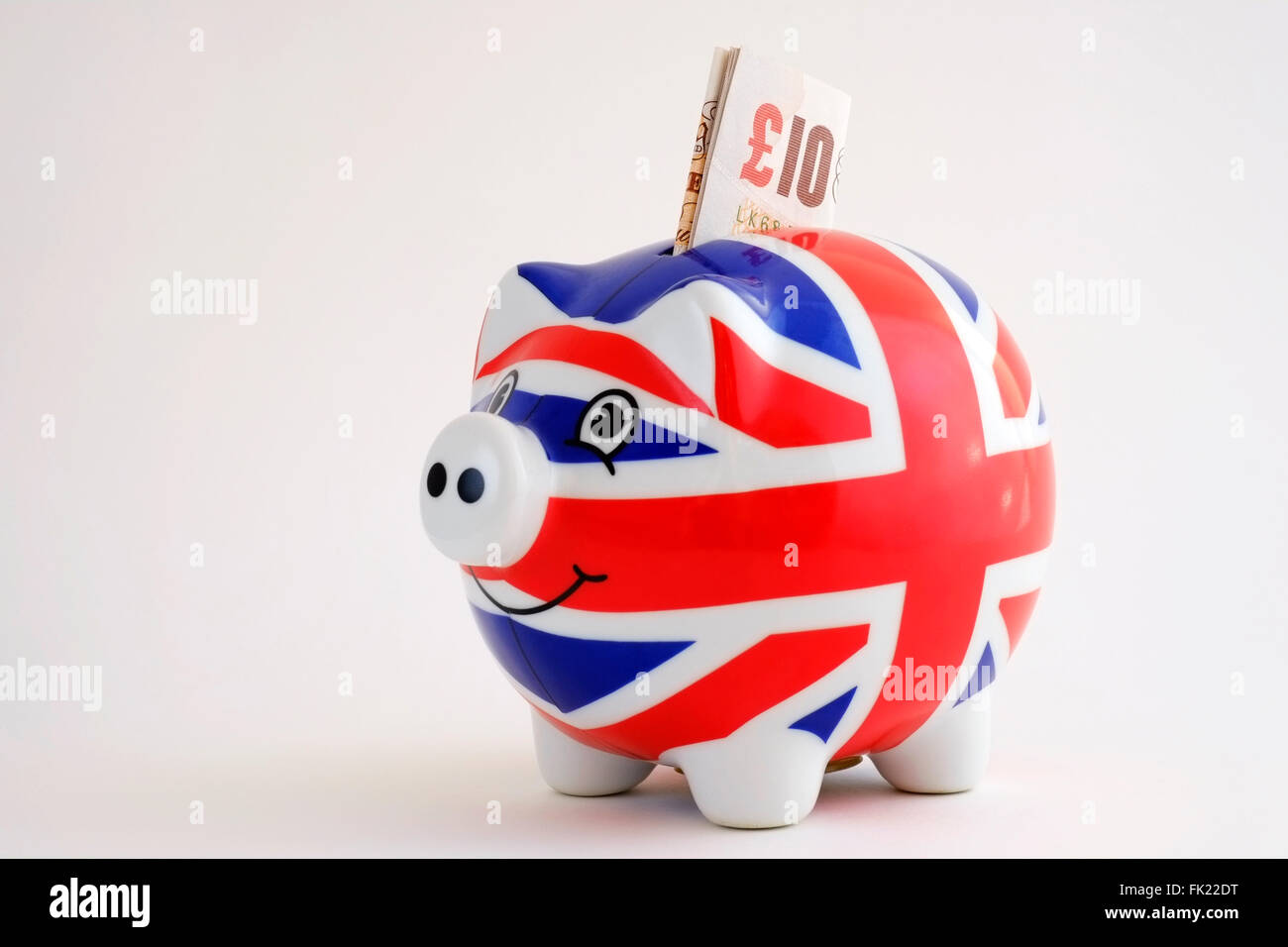 union jack flag piggy bank with sterling banknote ten pounds sticking out of top Stock Photo