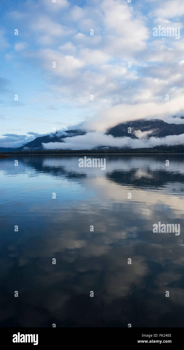 Still water in Southeast Alaska with cloud reflections at sunset. Stock Photo