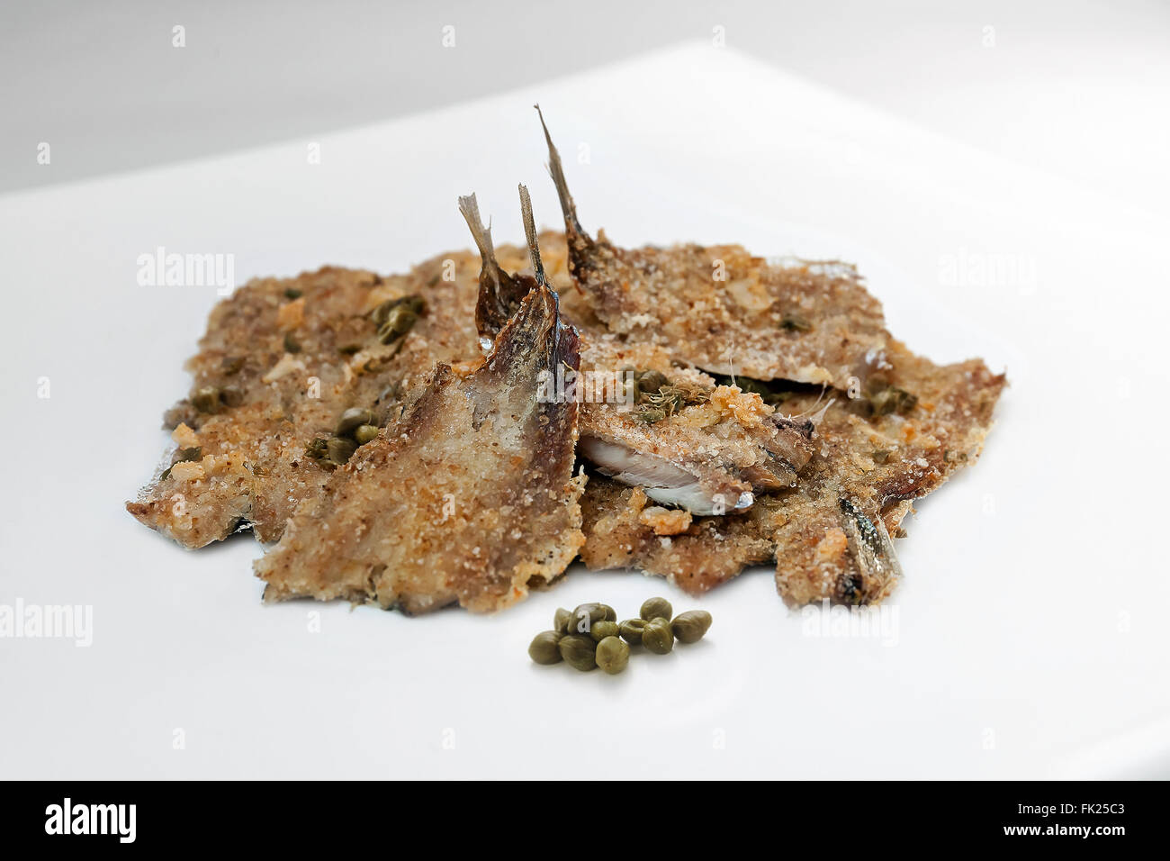 Anchovies baked with capers and breadcrumbs. Photographed in the studio