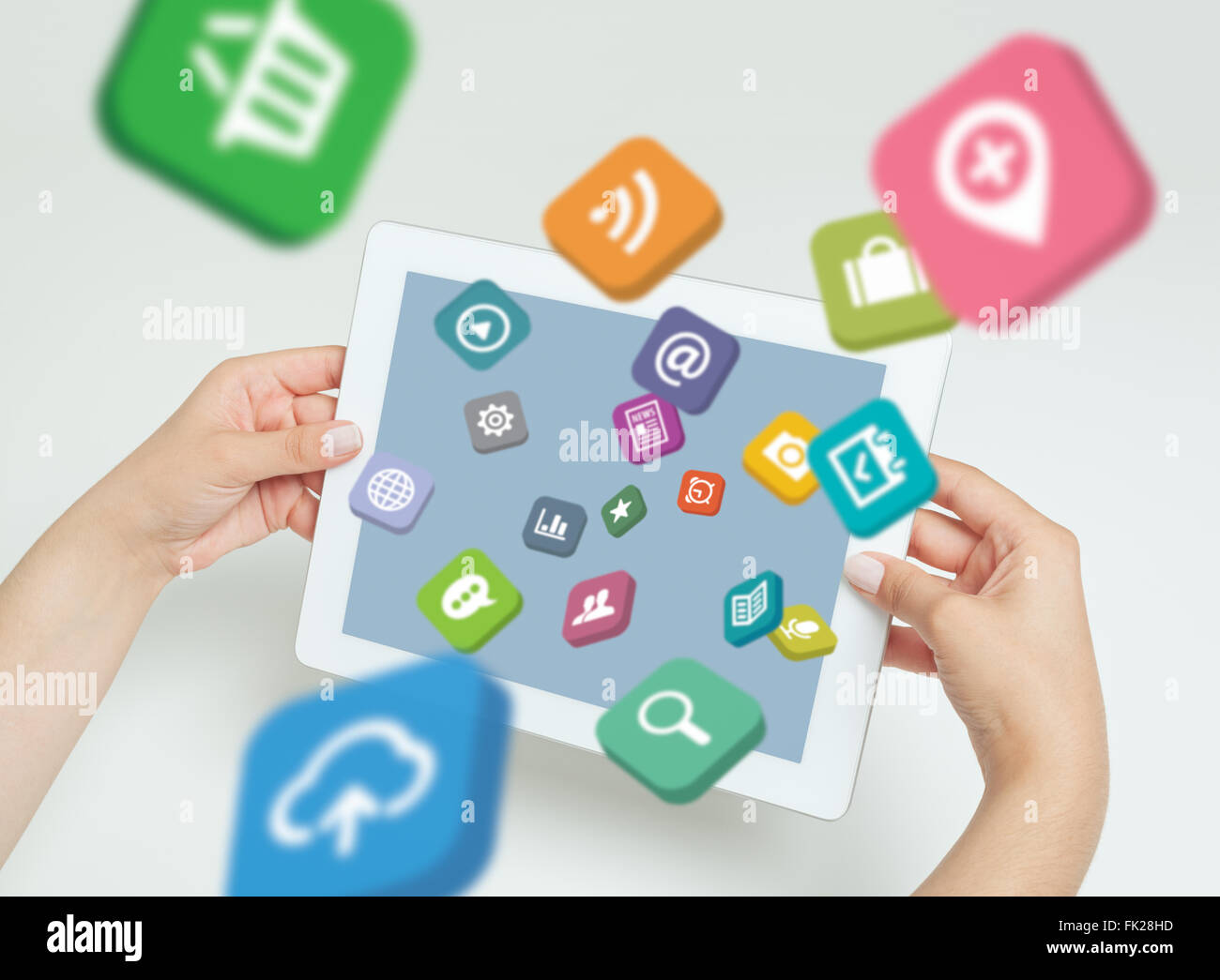 female hand touching screen and application icons fly off the tablet computer. Stock Photo