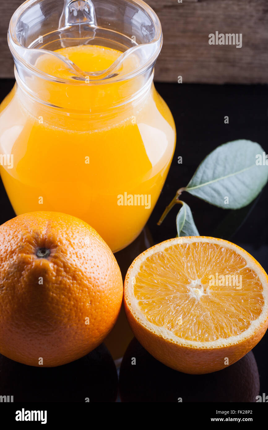 pitcher of fresh orange juice on black table Stock Photo