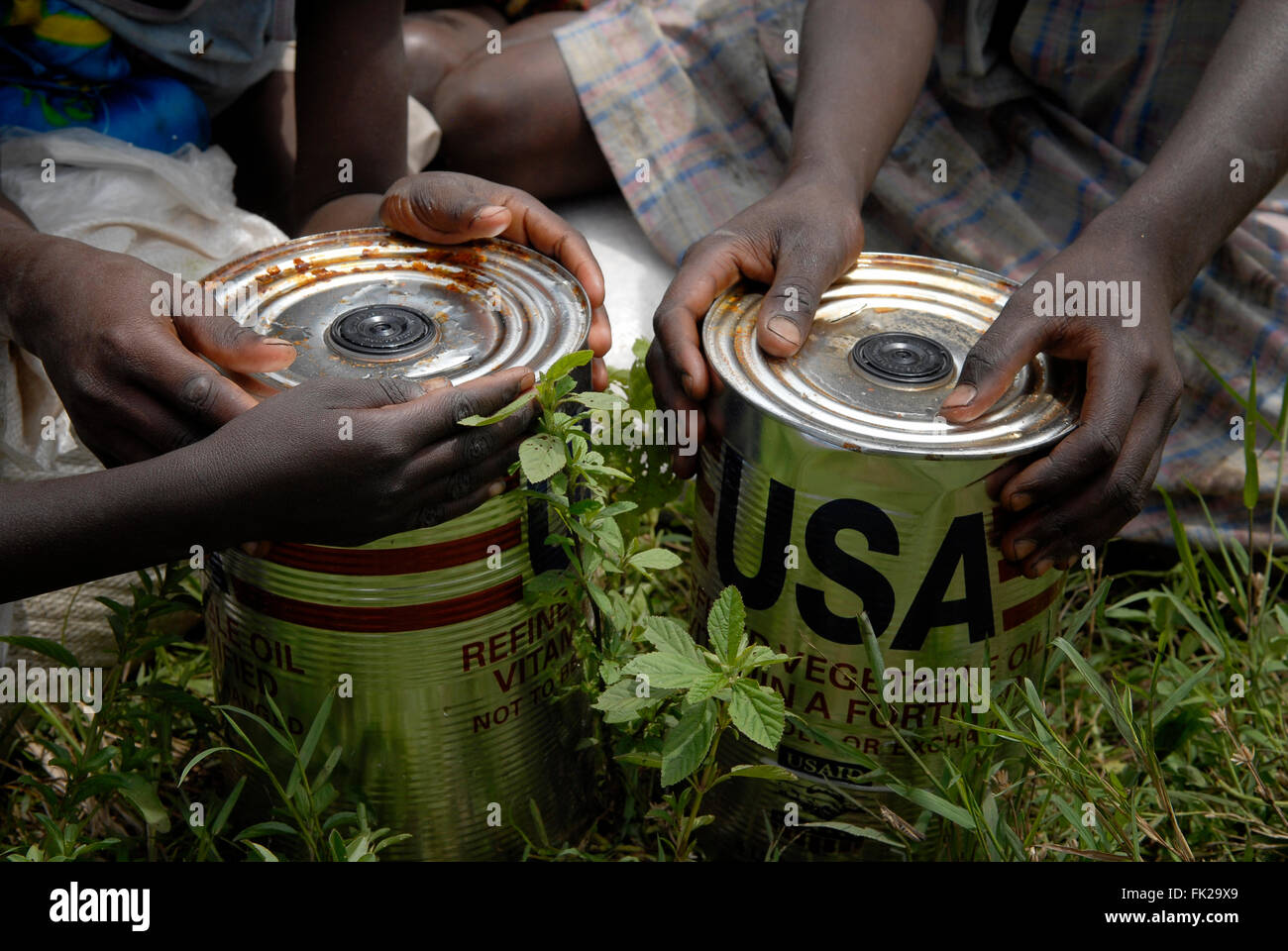 Internally displaced people hold cans of refined vegetable oil donated by USAID agency during UN World Food Programme food distribution in North Kivu province DR Congo Africa Stock Photo