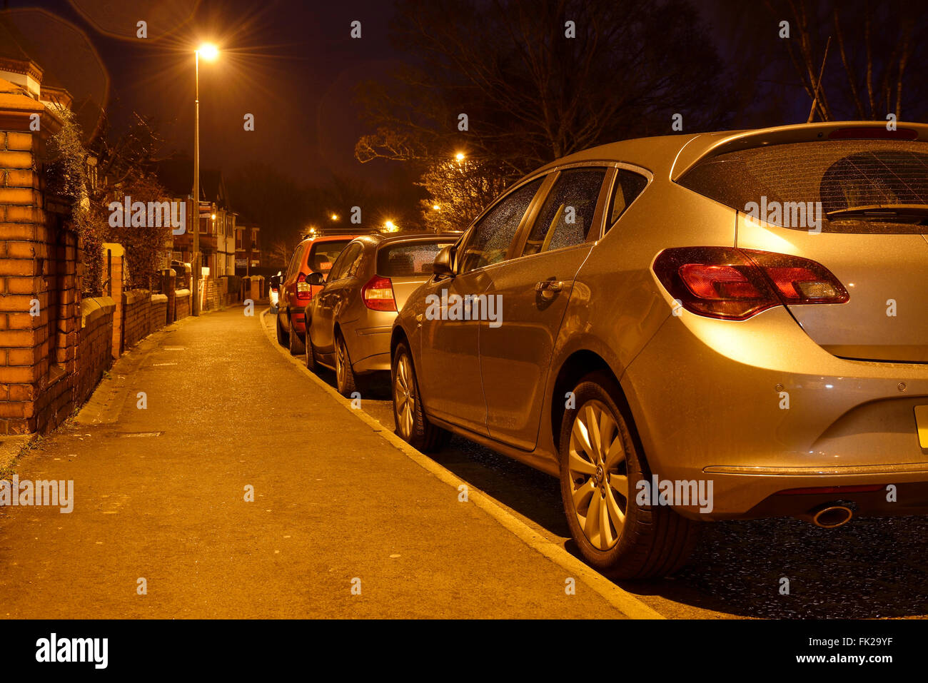 Cars parked on the side of a road at night Stock Photo