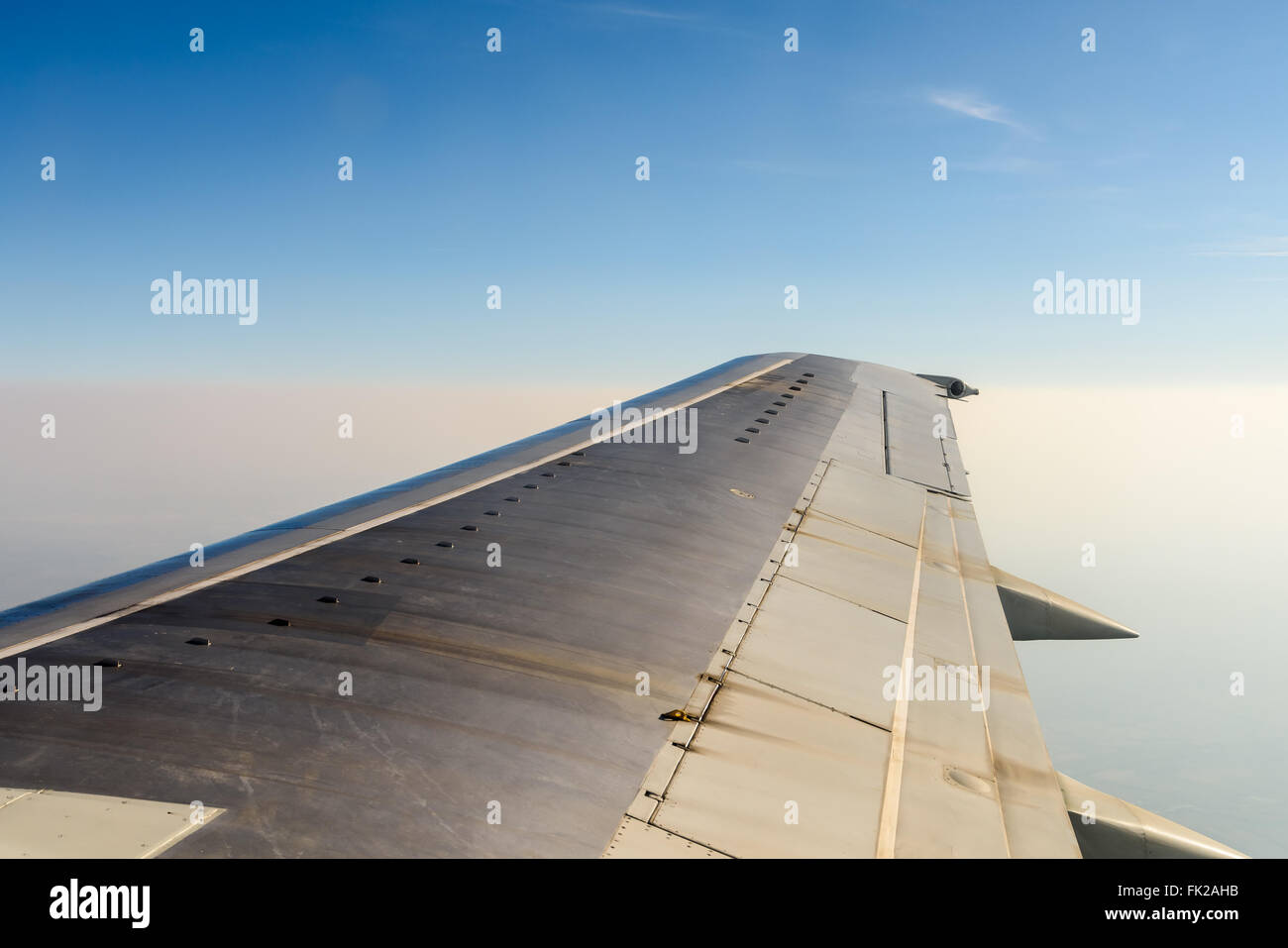 Window View Of Airplane Wing Flying Above Clouds Stock Photo