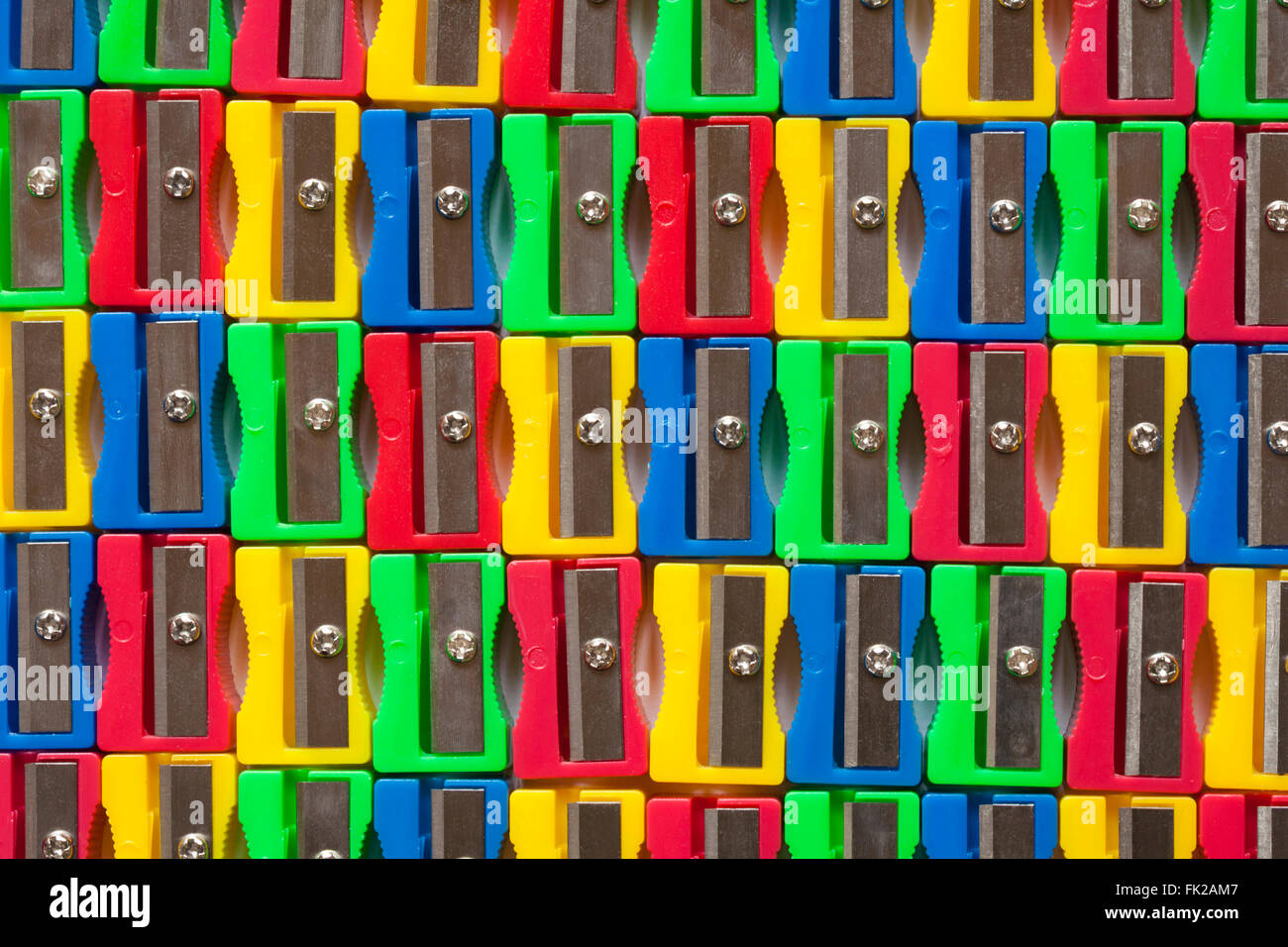 Rows of colourful red, yellow, green and blue plastic pencil sharpeners Stock Photo