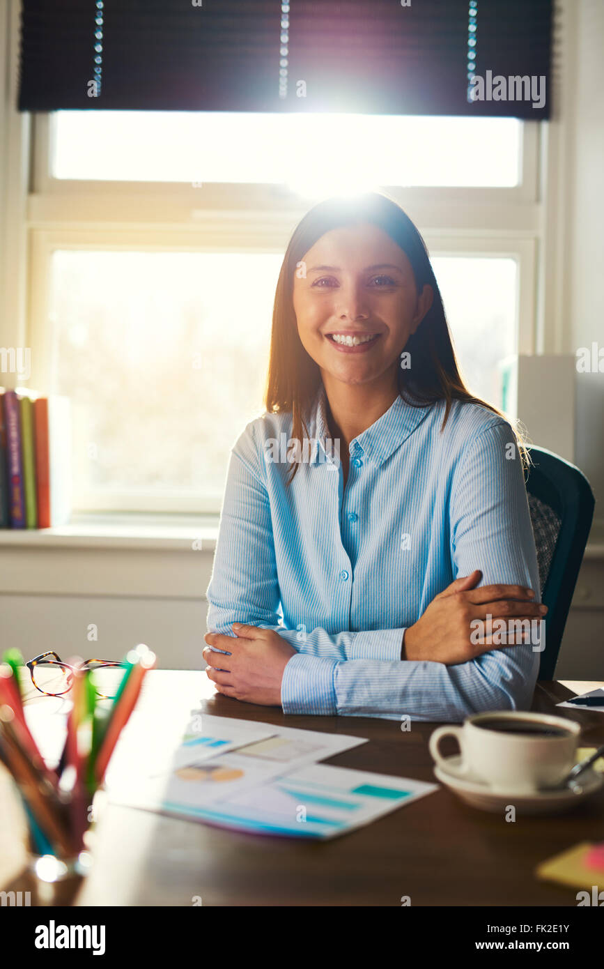Portrait of business woman sitting at her desk in a office smiling at ...