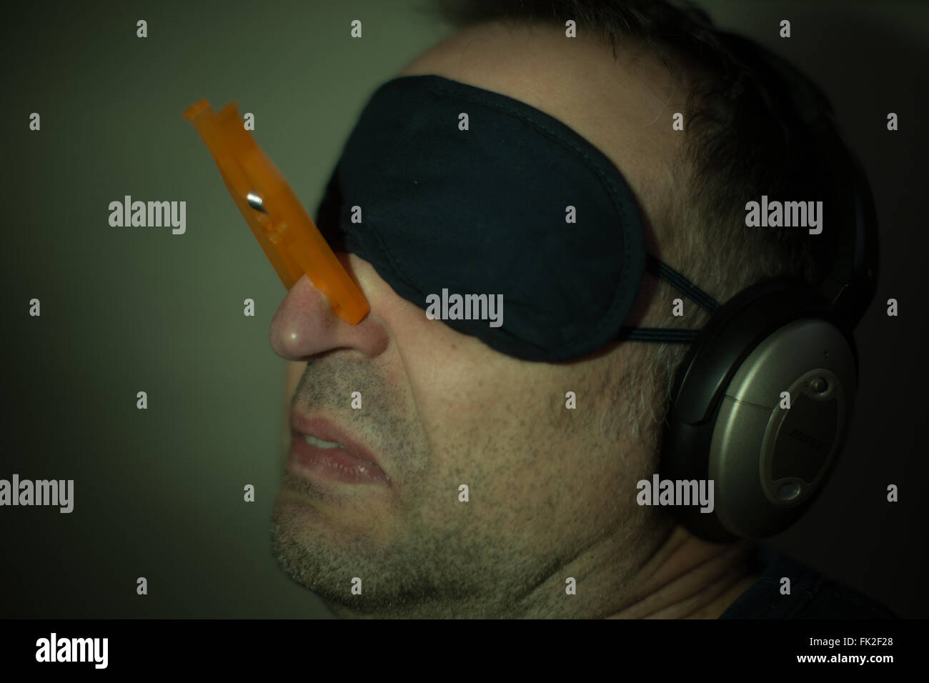 A man wears a clothes peg on his nose, headphones and an eye mask Stock  Photo - Alamy
