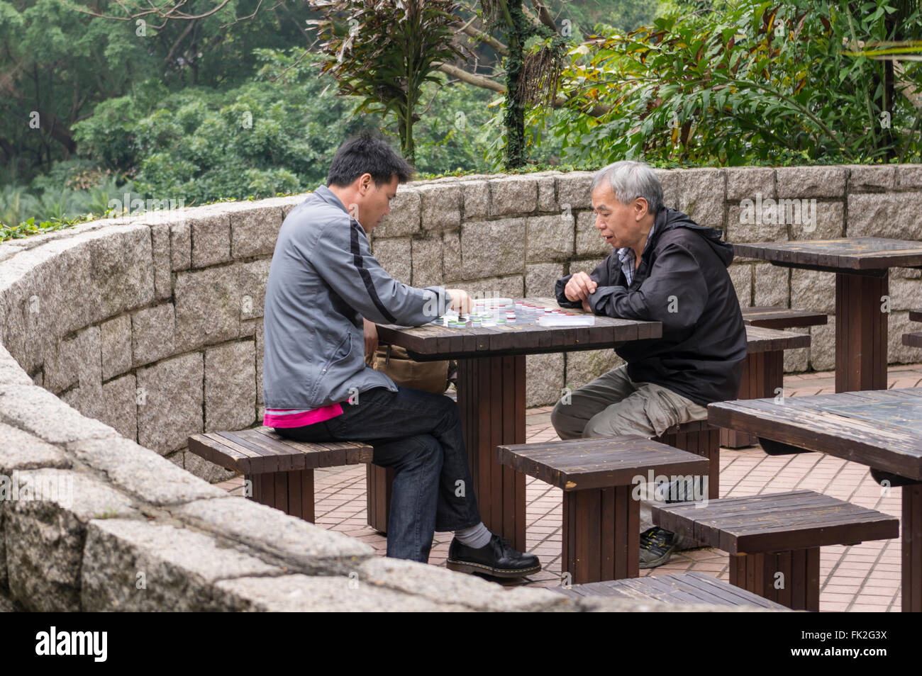 Two chinese men playing a board game in Kowloon Park, Tsim Sha Tsui, Kowloon, Hong Kong, China. Stock Photo