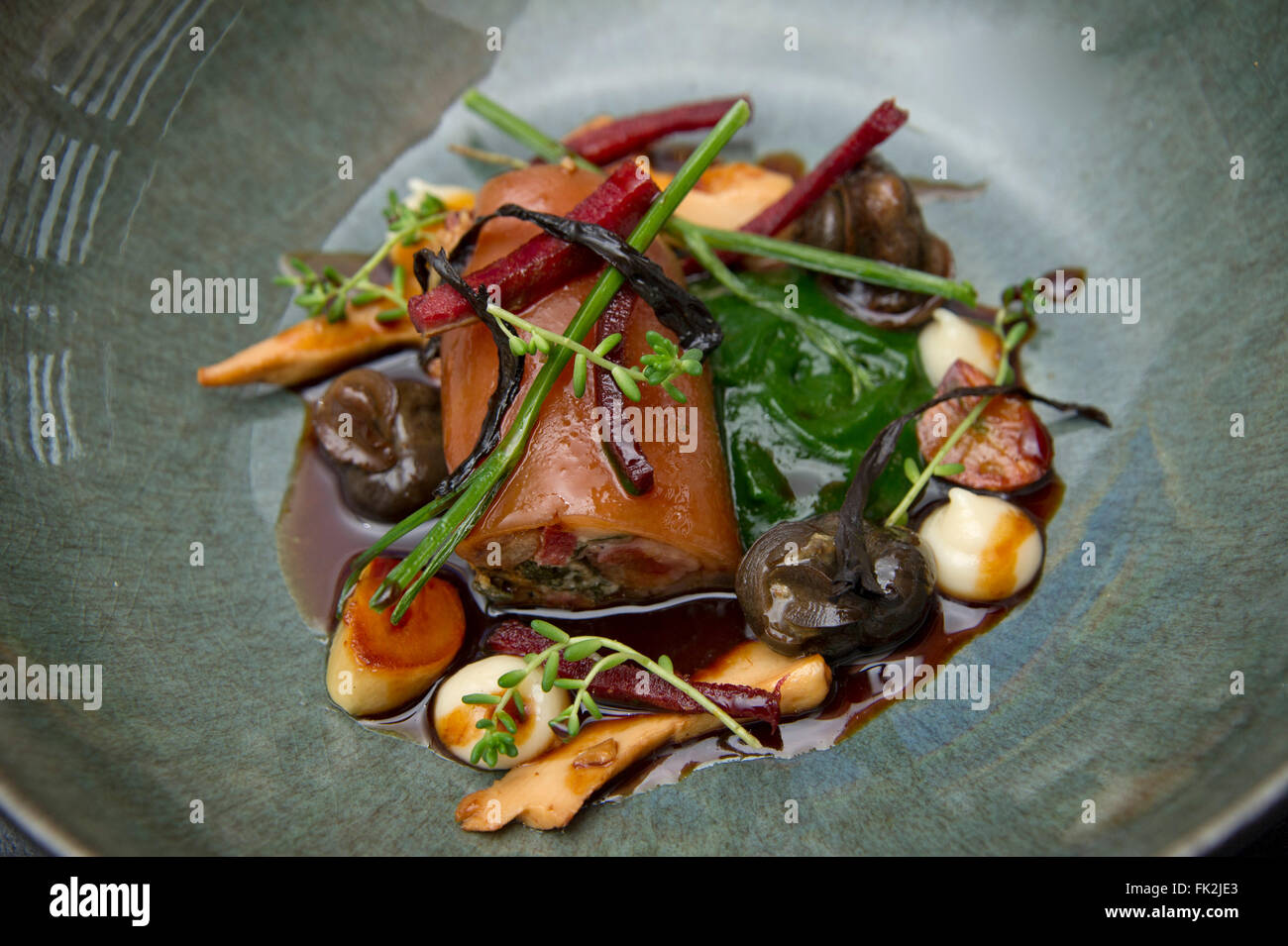 Pigs trotters stuffed with snails and ox tongue with roasted garlic cream.a UK food cuisine restaurants cook cooking meal plate Stock Photo