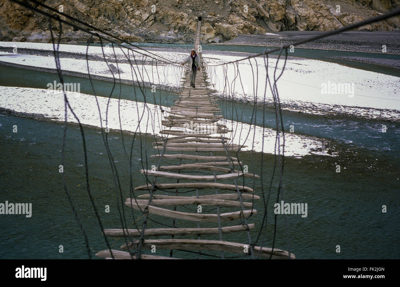 Man crossing the Hussaini bridge in Passu, old suspension bridge, above