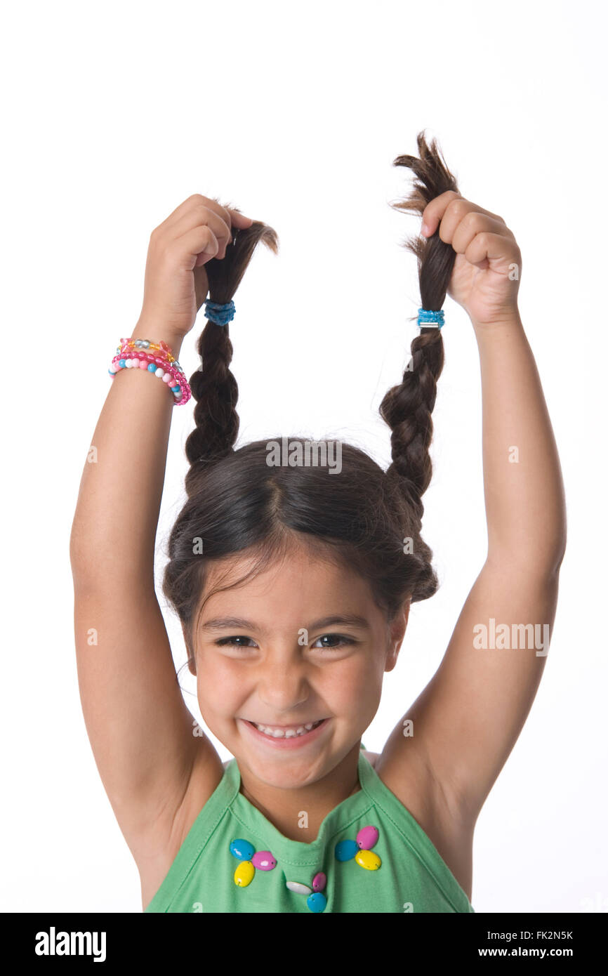 Little Girl Is Holding Her Pigtails High For Fun on white background Stock Photo
