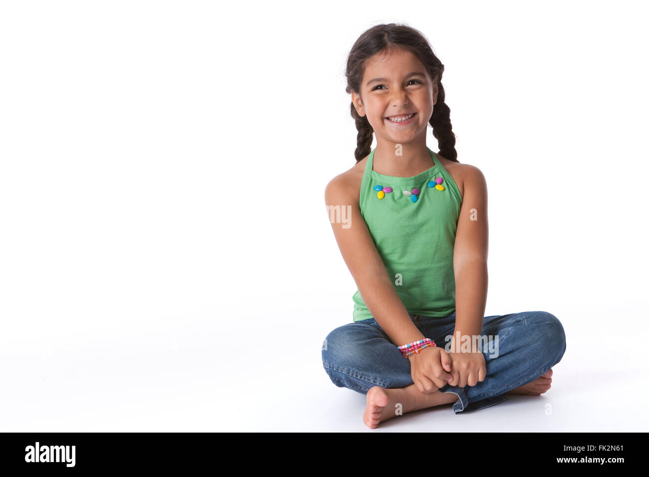 Little girl sitting on the floor with a happy expression on white ...