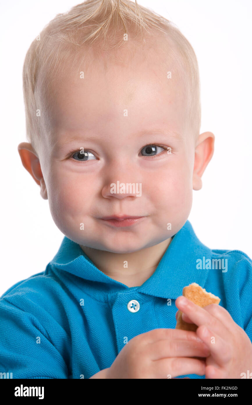 Toddler Boy Is Eating A Cooky With A Happy Expression on white background Stock Photo