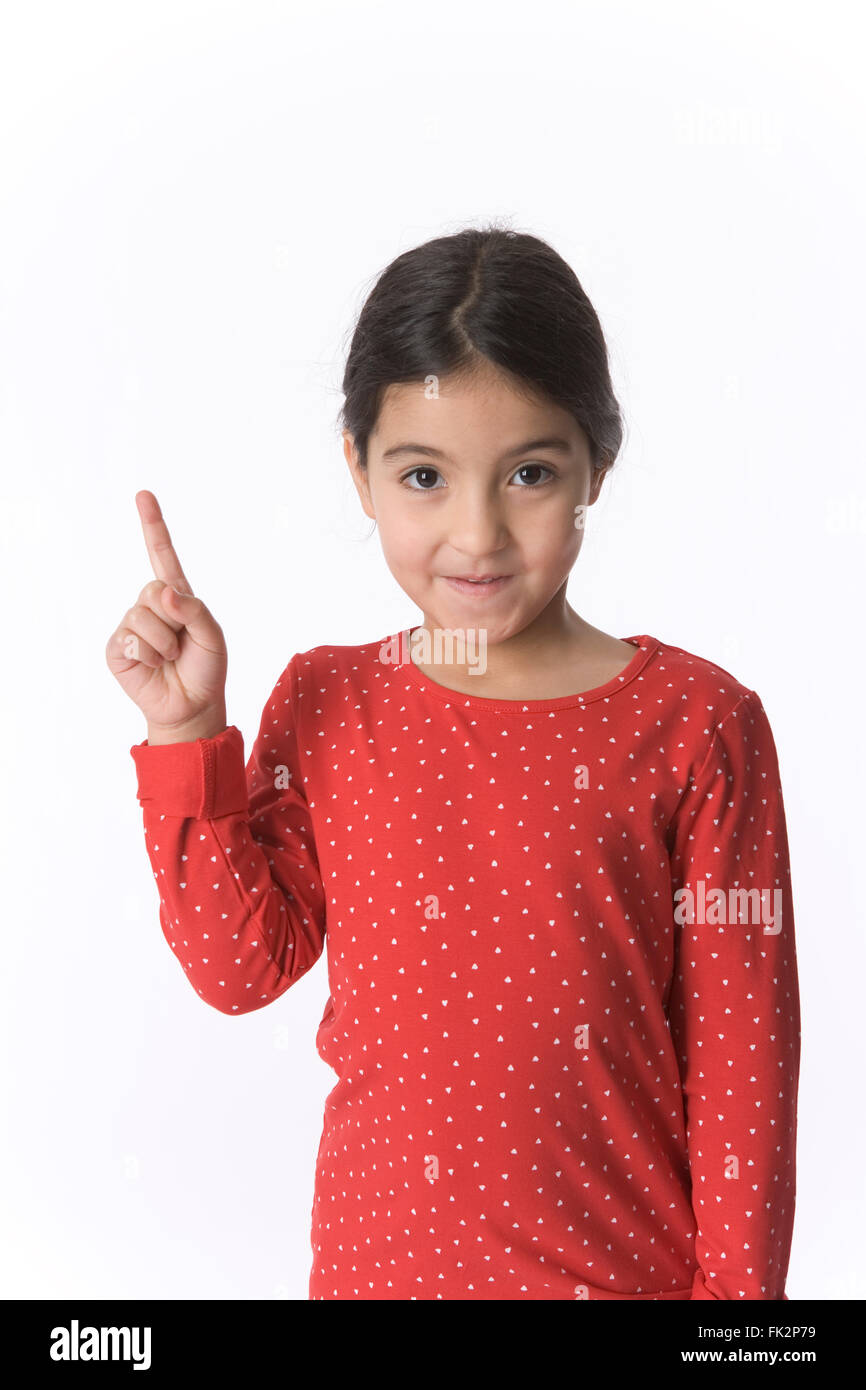 Little Girl Is Raising Her Finger With A Shy Expression on white background Stock Photo