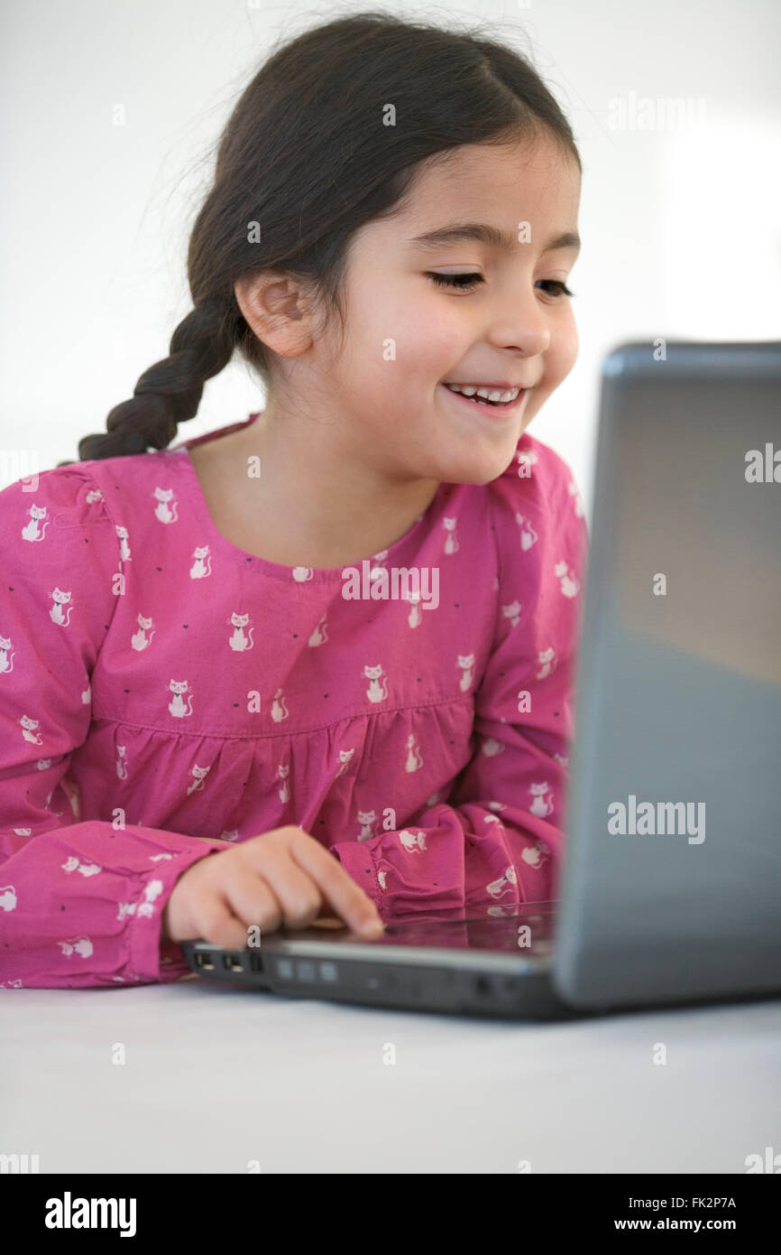 Smiling little Girl Behind A Laptop on white background Stock Photo - Alamy