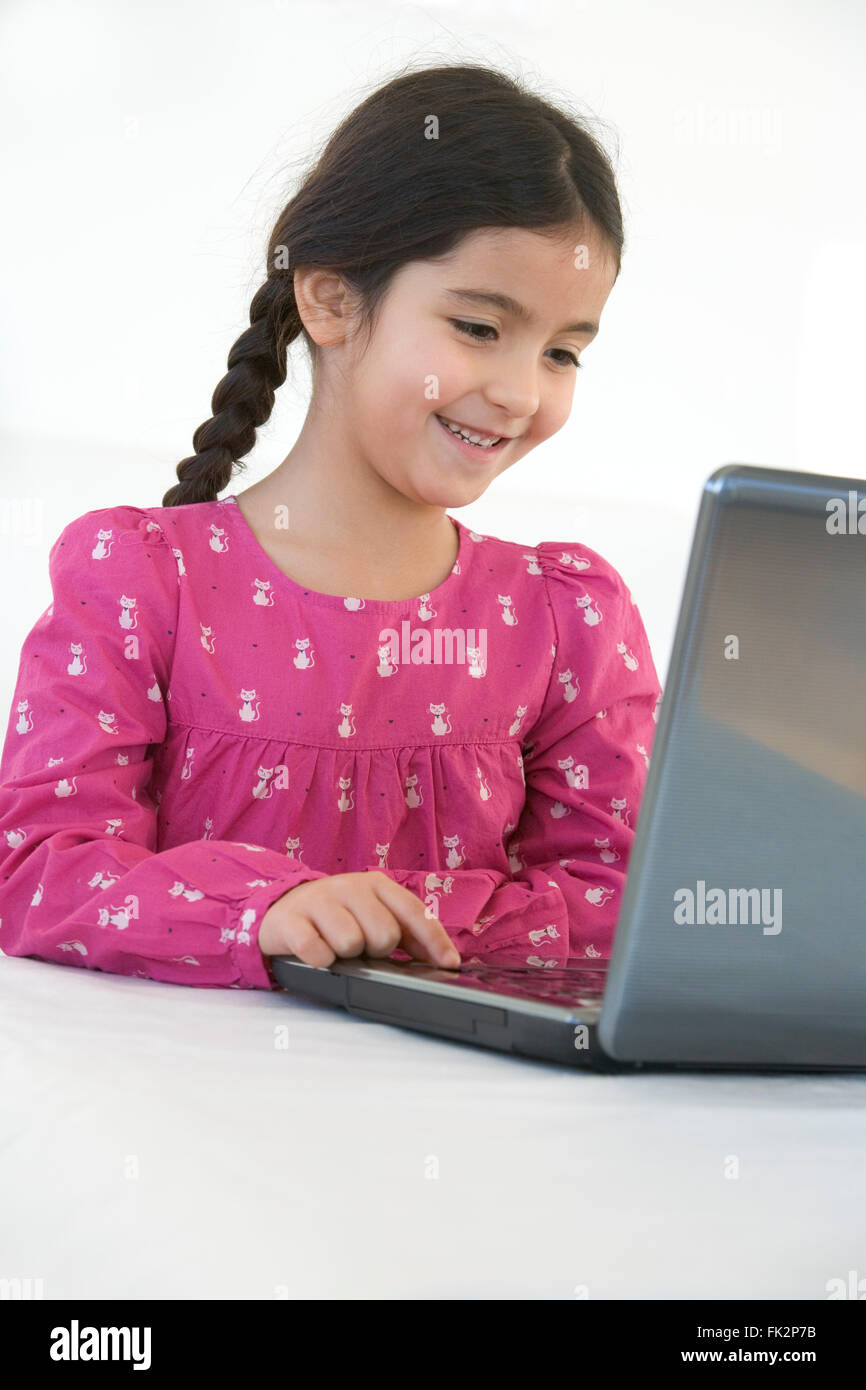 Smiling little Girl Behind A Laptop on white background Stock Photo - Alamy