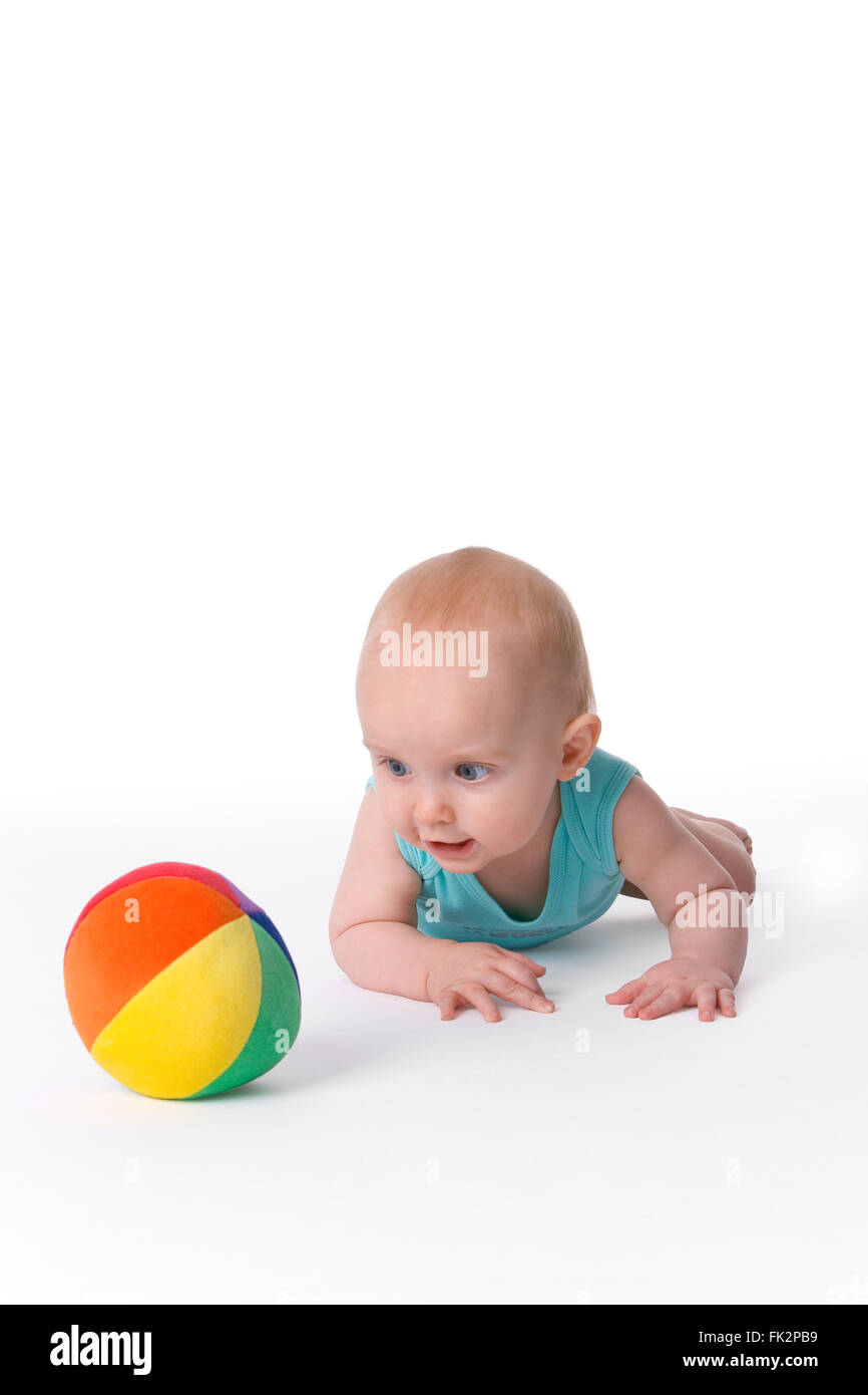 Baby Boy Is Crawling Towards A Colored Toy Ball on white background Stock Photo