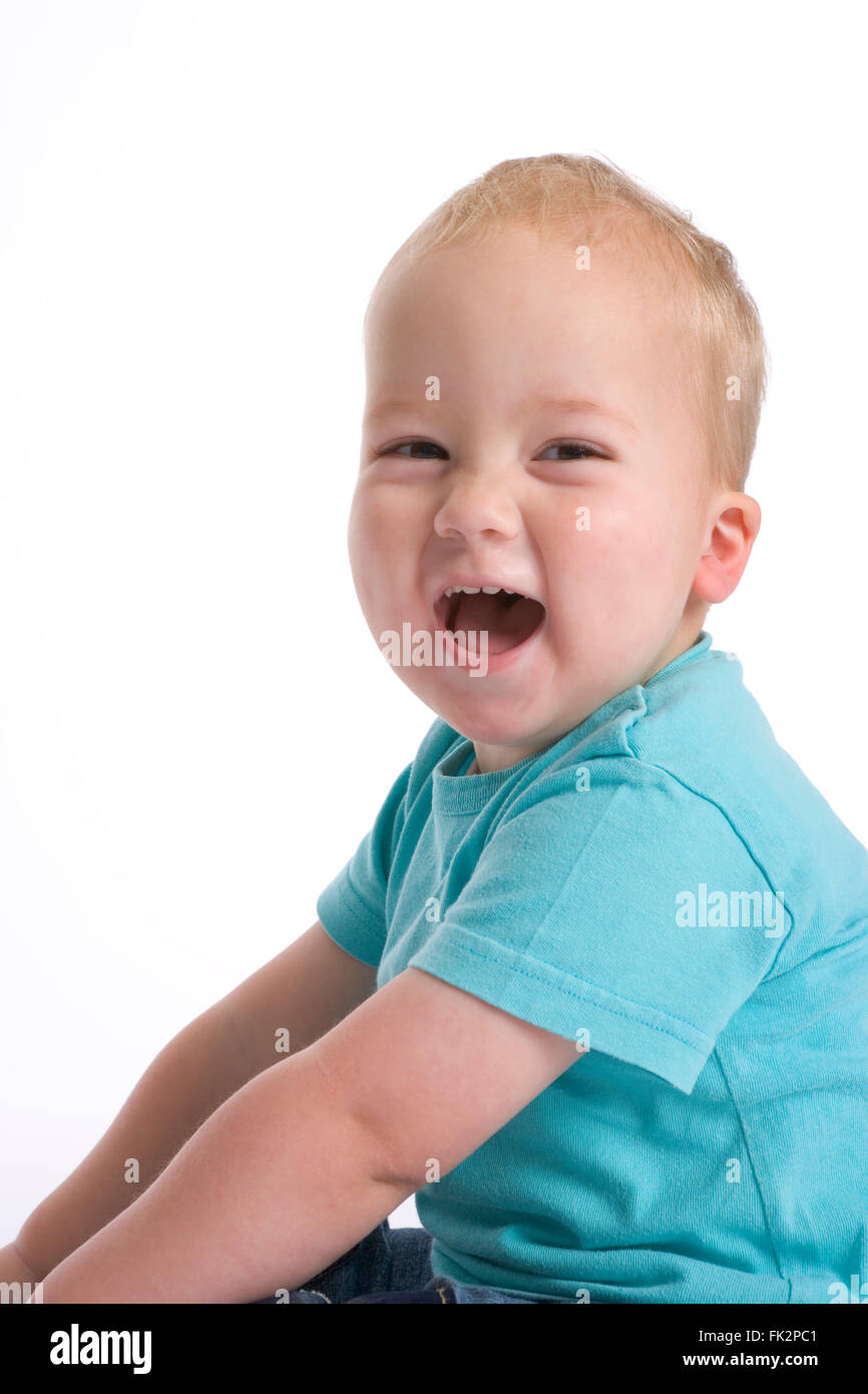 Toddler Boy Sitting On The Floor And Is Laughing Loud on white background Stock Photo