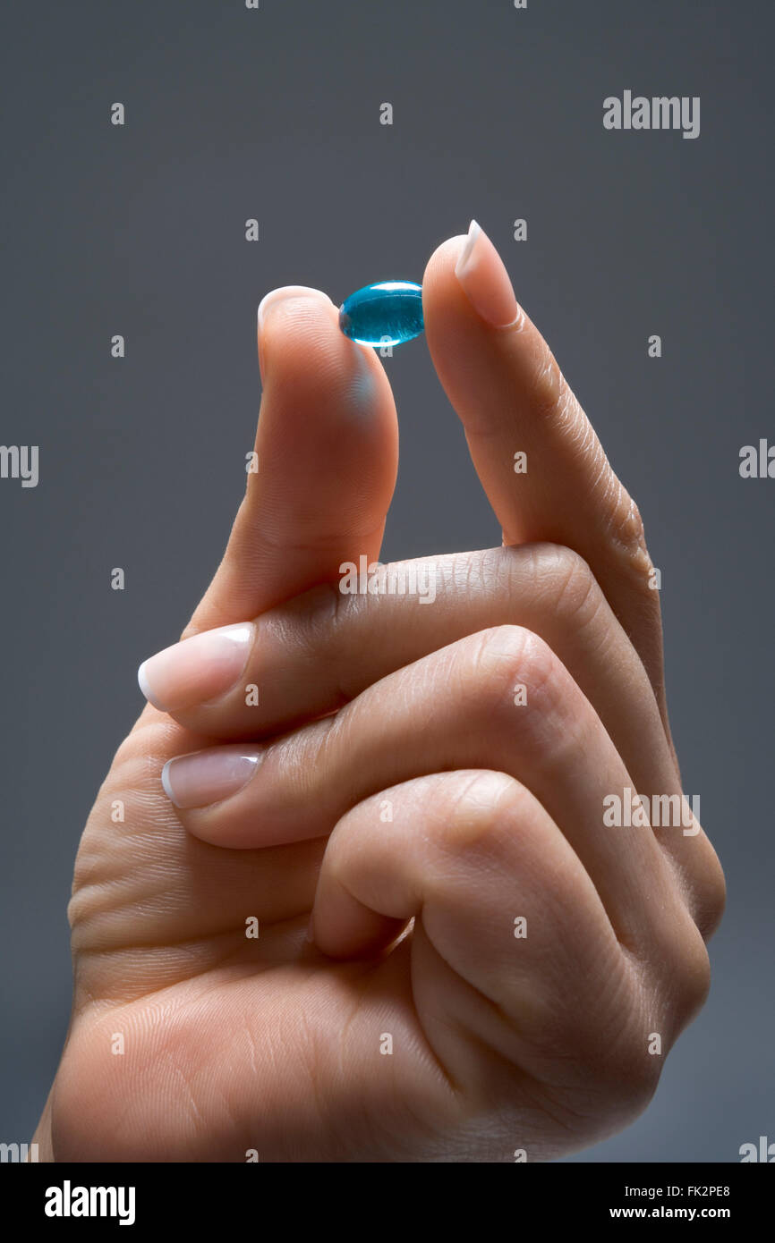 Close Up Of Fingers Holding A Blue Capsule Stock Photo