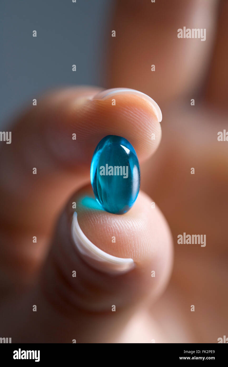 Close Up Of Fingers Holding A Blue Capsule Stock Photo