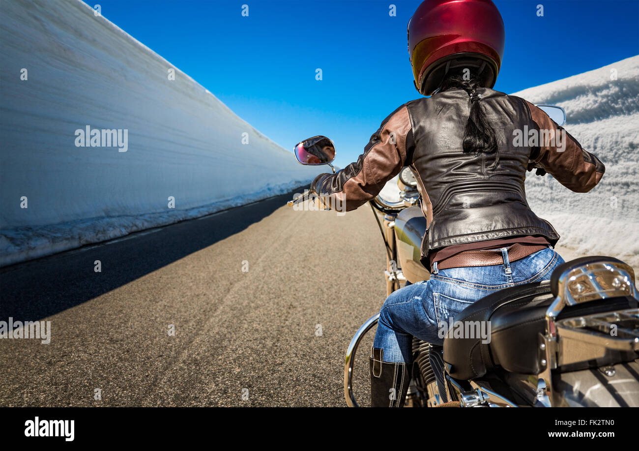 Biker girl rides a mountain road with high snow wall in Norway. First ...