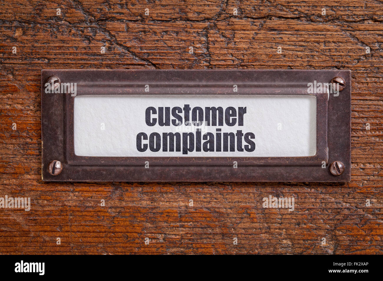 customer complaints  tag - file cabinet label, bronze holder against grunge and scratched wood Stock Photo