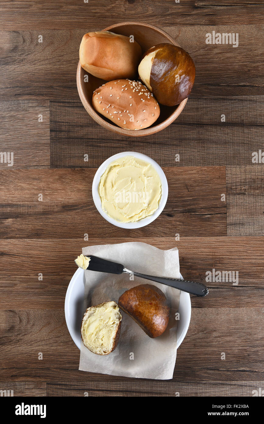 Bowl of assorted dinner rolls with butter crock and bread plate. Vertical format from a high angle. Stock Photo