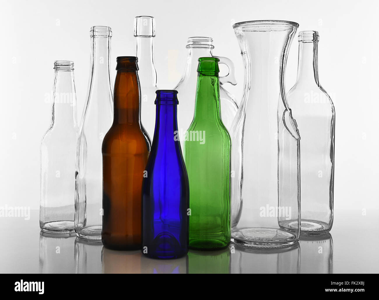 Empty Glass bottles on white with reflection. Clear glass and colored bottles. Stock Photo