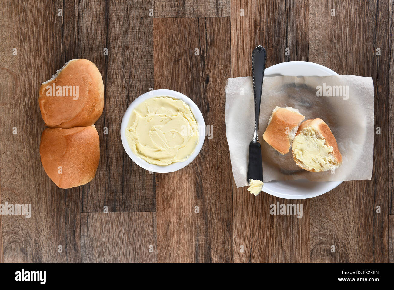 Overhead view of Dinner rolls Bread Plate and Butter Crock on a rustic wood table. Stock Photo