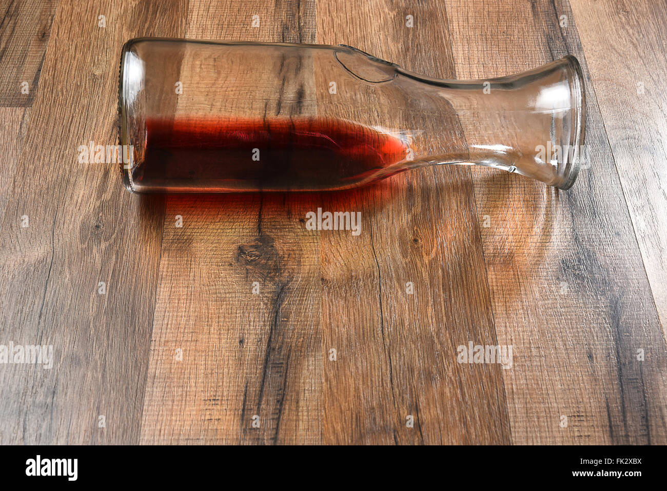 High angle view of a carafe of wine on its side on a wood table. Stock Photo