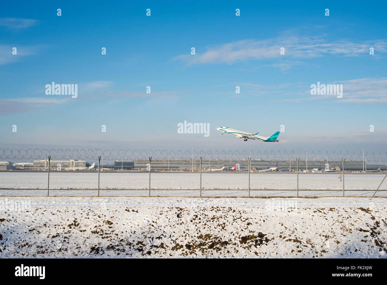 Embraer ERJ 195 airplane takes off at Munich Airport south runway on a sunny winter afternoon - all Logos removed Stock Photo