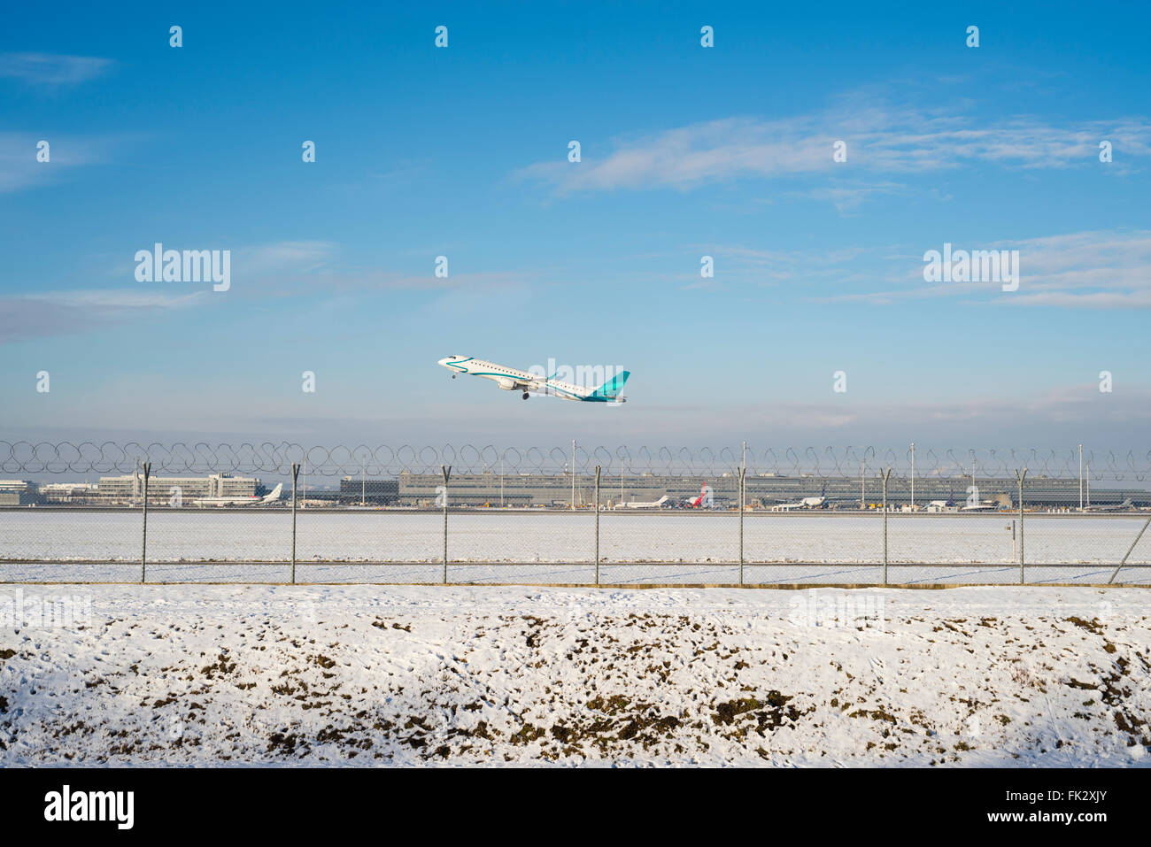 Embraer ERJ 195 airplane takes off at Munich Airport south runway on a sunny winter afternoon - all Logos removed Stock Photo