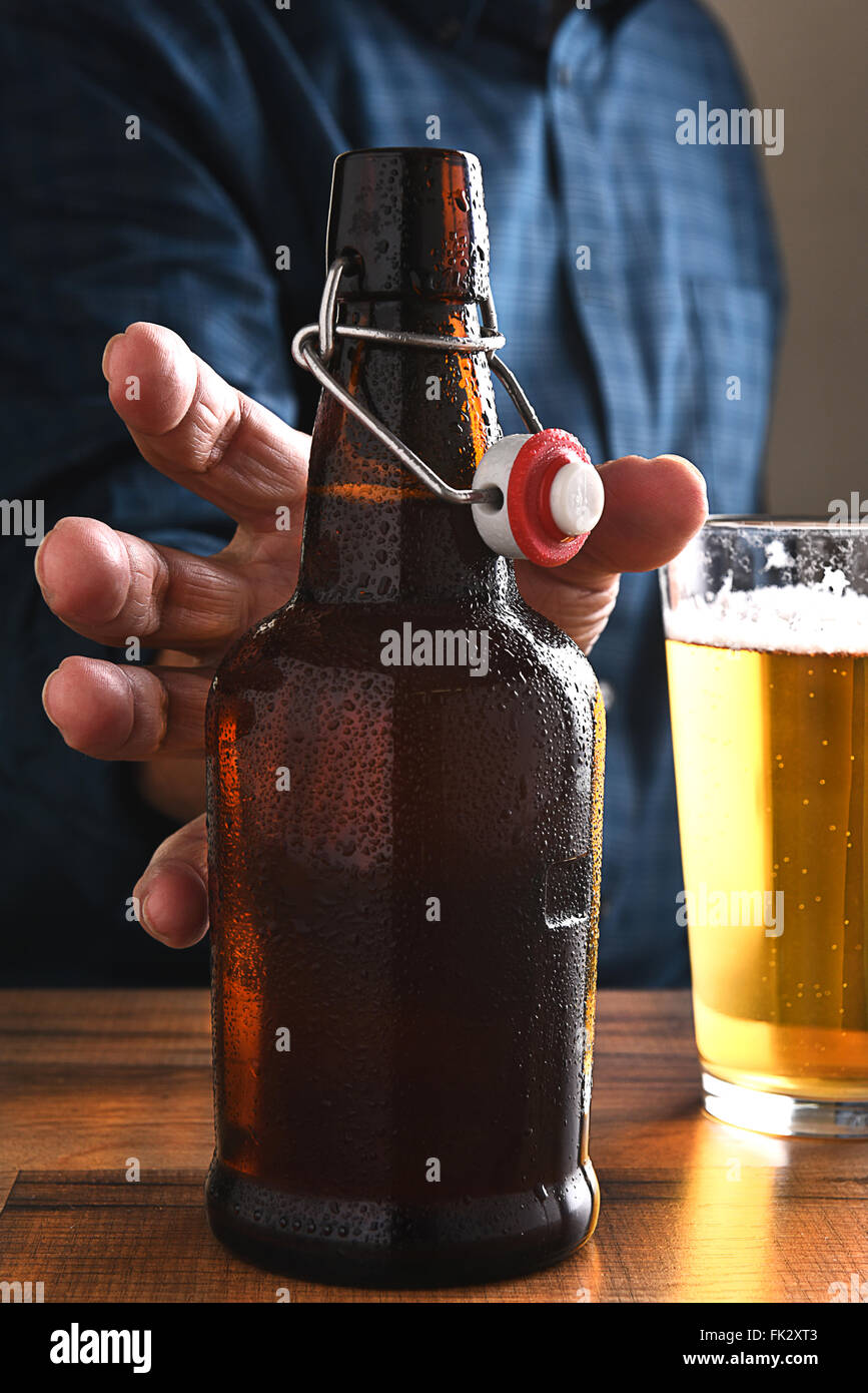 Closeup of a man reaching for an old fashioned swing top beer bottle. Stock Photo