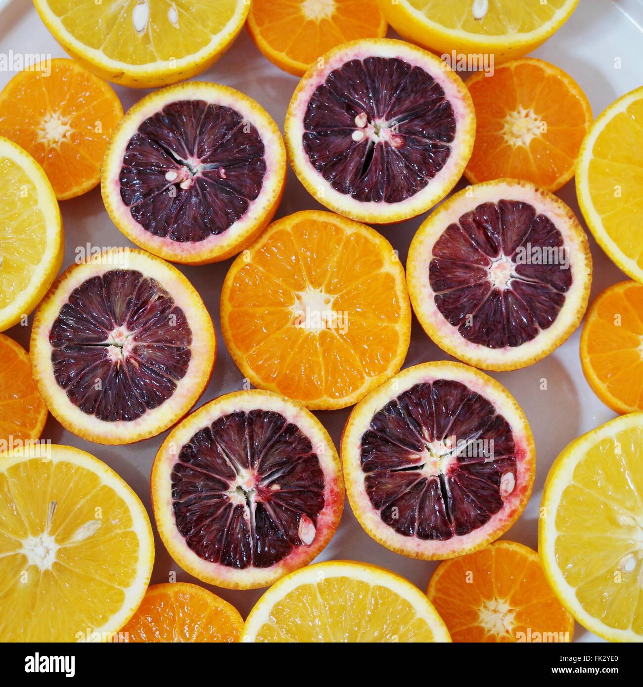 Ruby red blood oranges, navel oranges, and clementines cut in half on a ...
