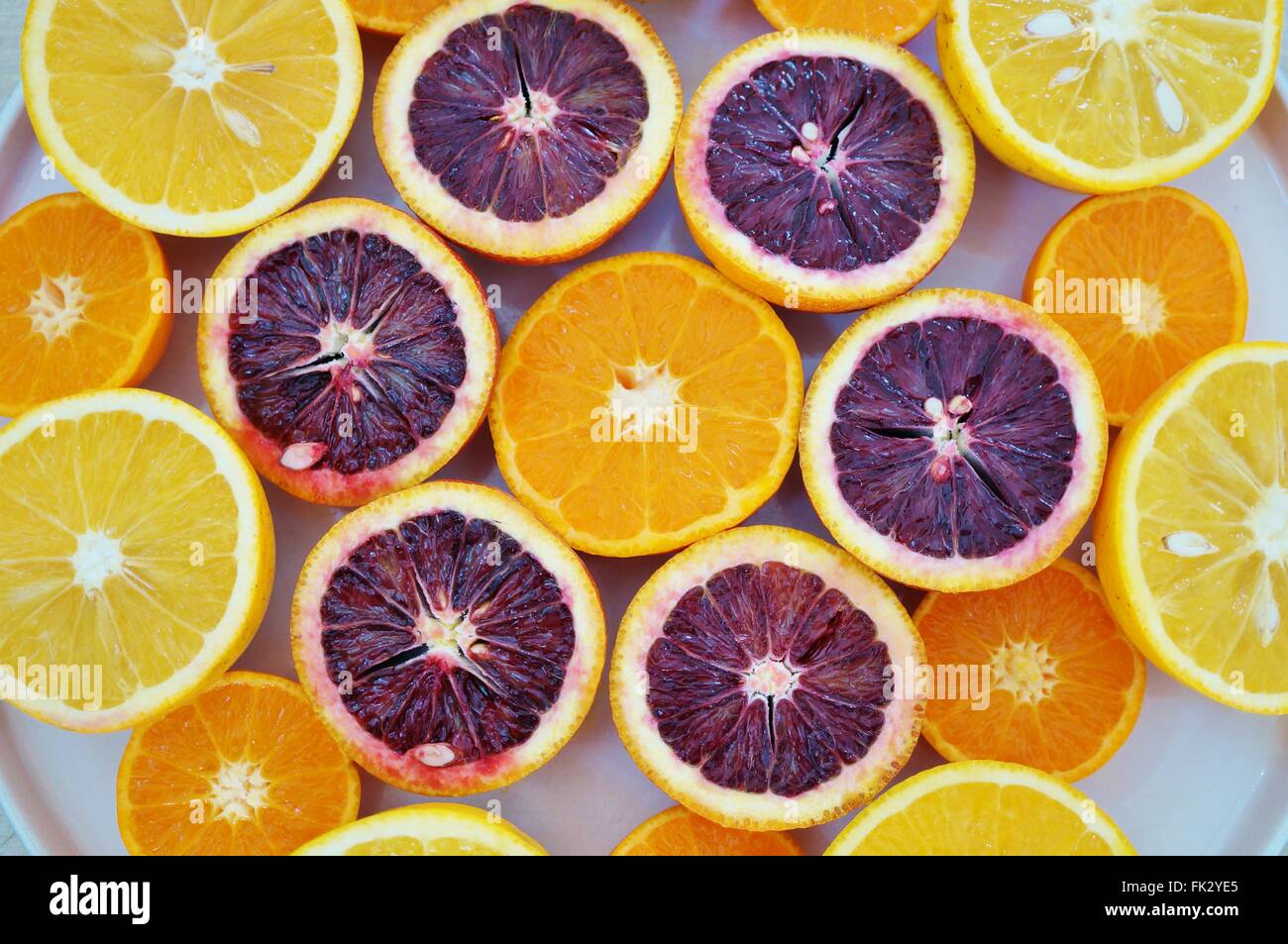 Ruby red blood oranges, navel oranges, and clementines cut in half on a