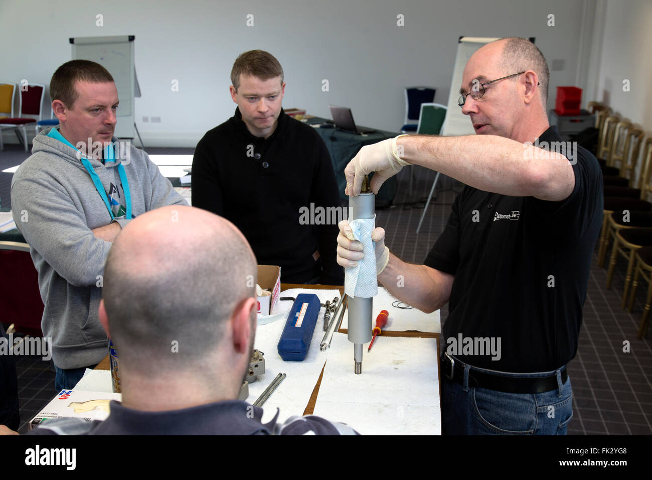 Adult men being taught engineering and pneumatics by qualified engineer instructor. Stock Photo
