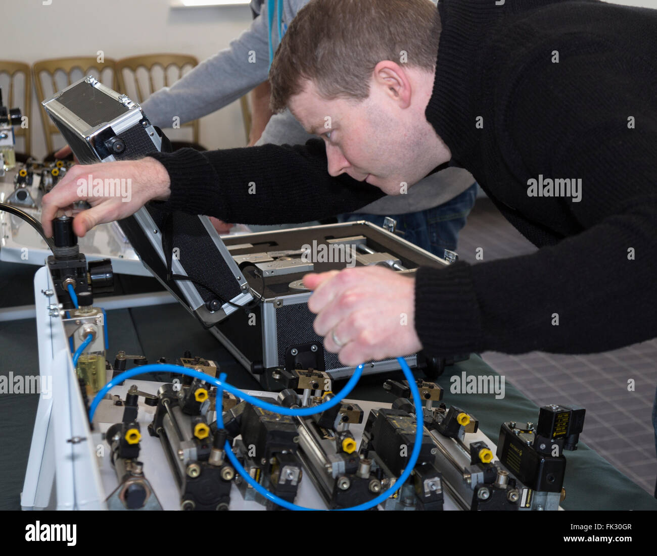Adult men being taught engineering and pneumatics by qualified engineer instructor. Stock Photo