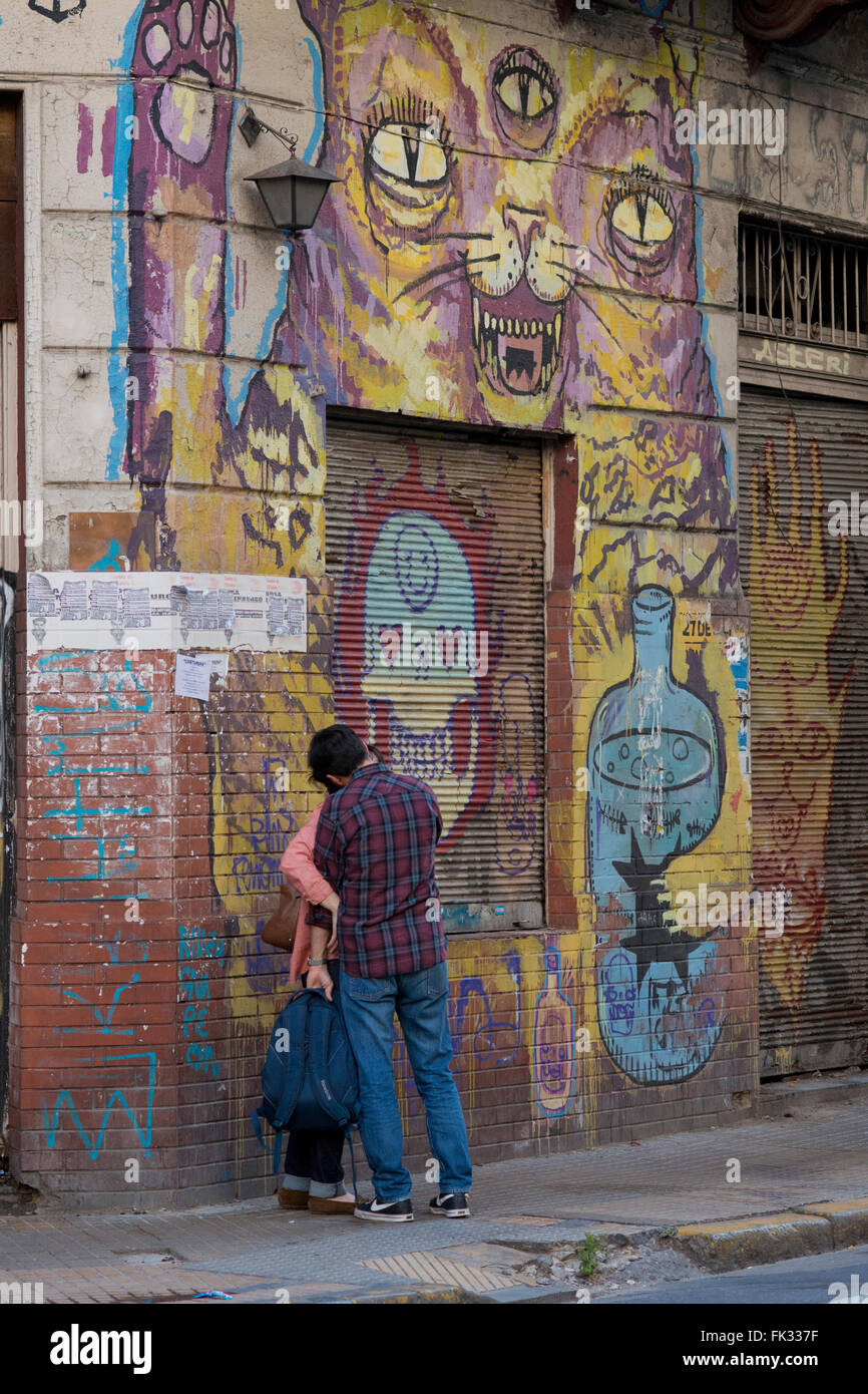 two youns embraced and kissing in front of a mural painting in San Telmo, barrio of Buenos Aires Stock Photo