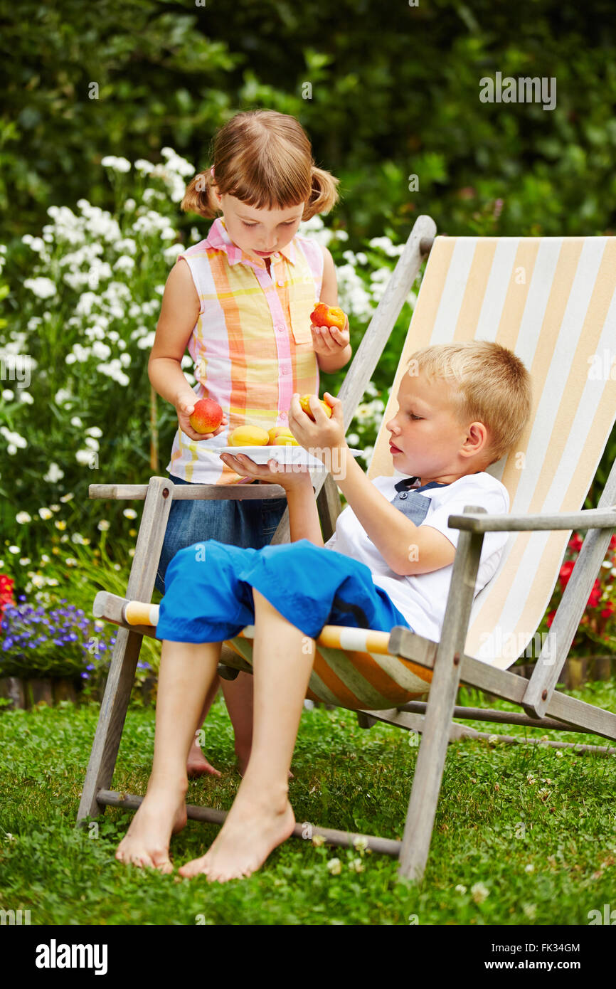 Two children sharing fresh fruits in a garden after the harvest Stock Photo
